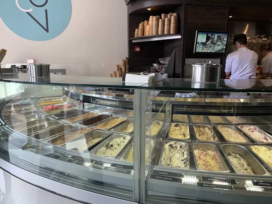 The counter with an employee and the different types of scoop ice cream