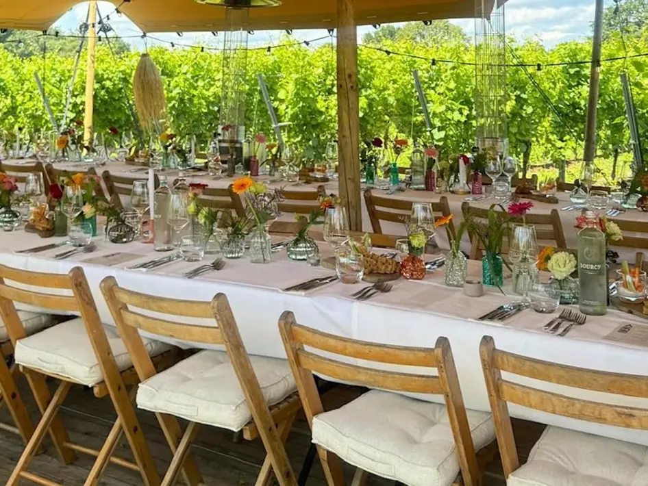 Een lange tafel staat gedekt voor de culinaire ervaring Tussen de Wijnranken van Wijngoed Thorn.