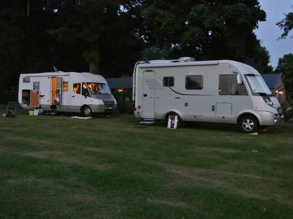 Zwei Wohnmobile stehen in der Abenddämmerung auf den Wohnmobilstellplätzen von The Pioneer