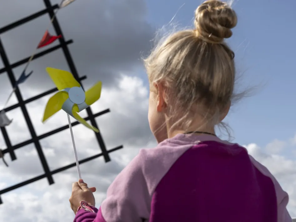 Girl with a pinwheel at the Hompesche Molen while the sails turn against the sky