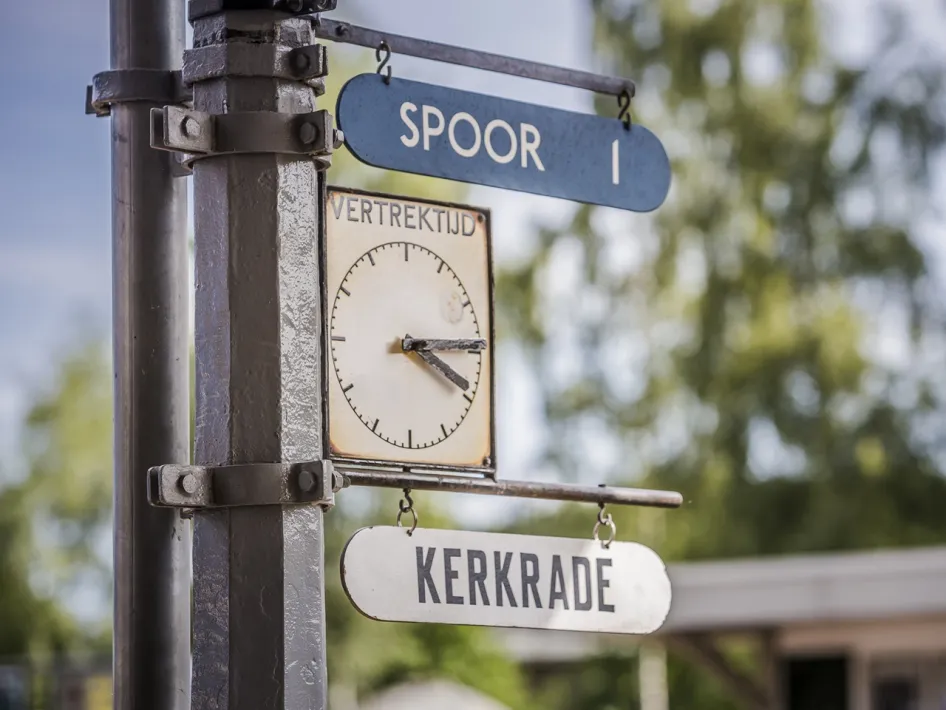 Alte Bahnhofsuhr mit Abfahrtszeit und Schildern Richtung Gleis 1 und Kerkrade.
