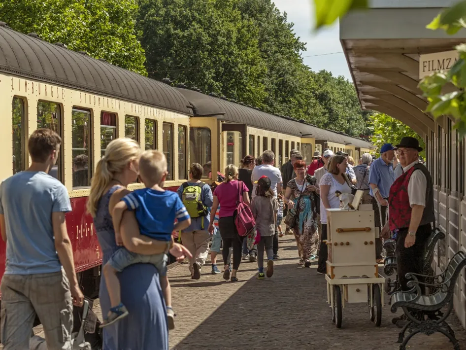 Busy platform scene at Simpelveld station with a historic train and visitors.