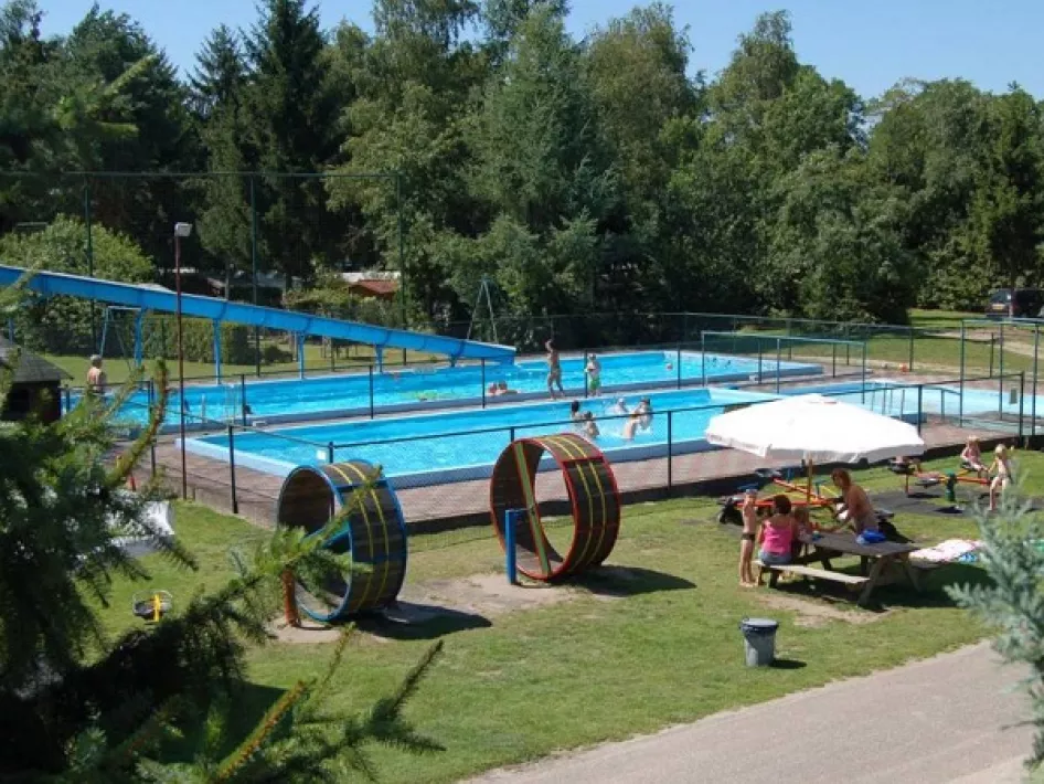 The outdoor pool at Camping de Oude Barrier where children play in the water and people lie under the parasol