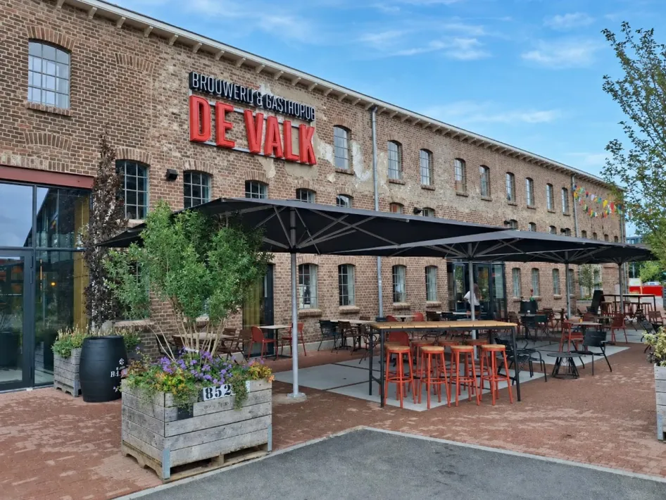 Backsteinfassade der Brouwerij & Gasthof De Valk mit Terrasse und großen Sonnenschirmen bei De Pannenfabriek in Echt.