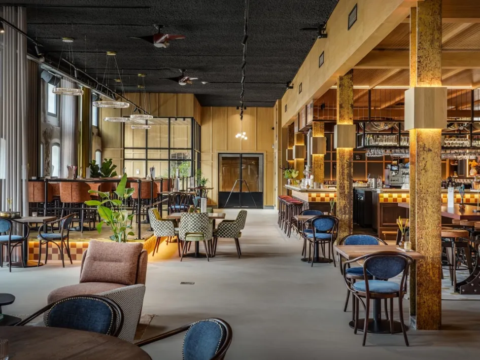 Innenraum von De Valk mit einer großen Bar, Sitzbereichen und warmer Beleuchtung in De Pannenfabriek in Echt.