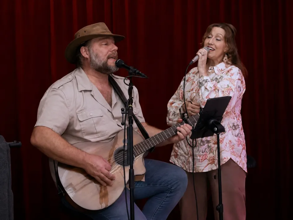 PEVE & Myra zingen samen op het podium, begeleid door akoestische gitaar.