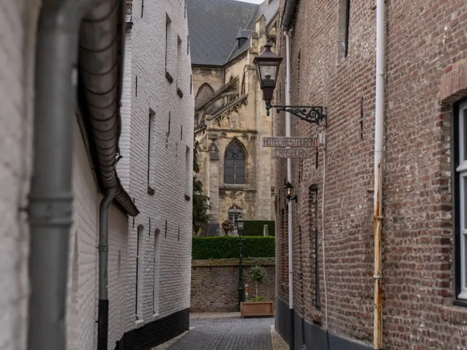 Smalle straat in Thorn met zicht op de kerk en het uithangbord van Hotel-Restaurant Crasborn