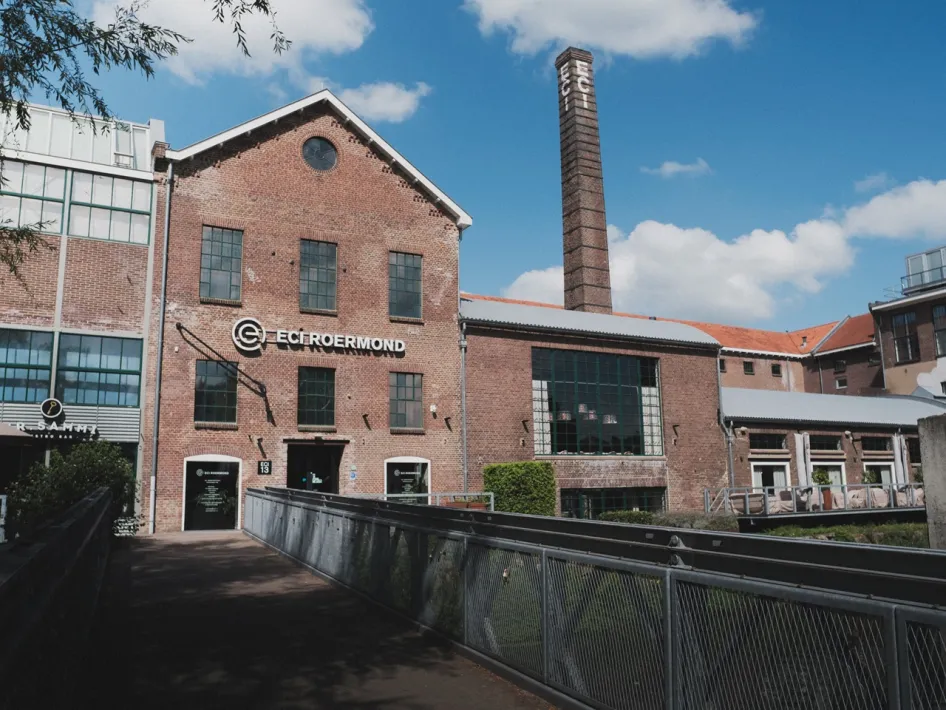 Buitenzijde van ECI Cultuurfabriek in Roermond met de karakteristieke fabrieksschoorsteen.