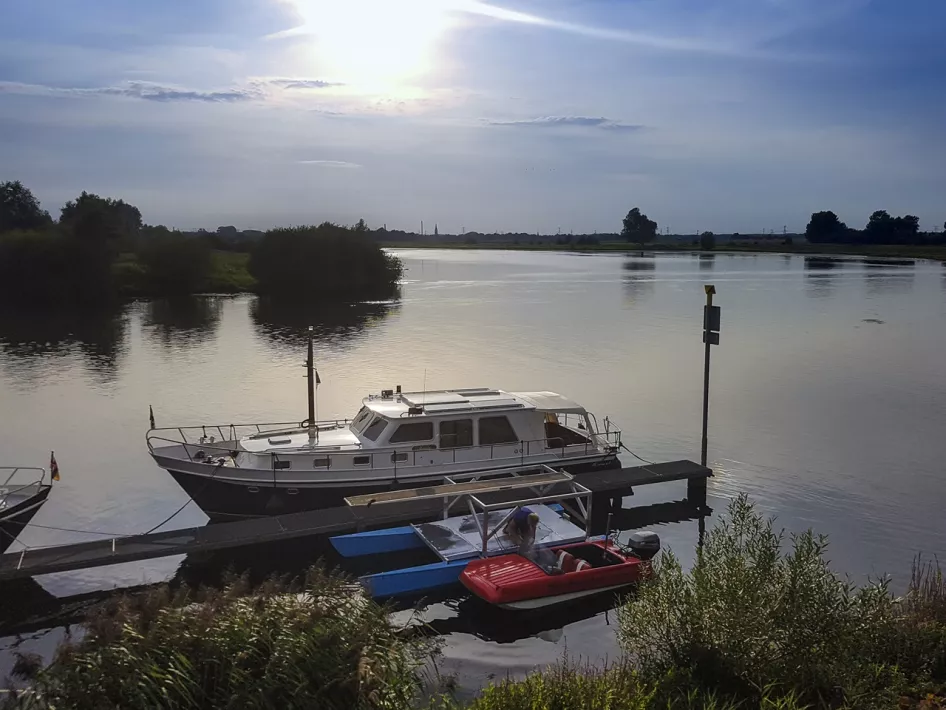 Uitzicht op het water met een aangemeerde boot bij vakantieverblijf Eind 6, gelegen aan de Maas in Asselt.
