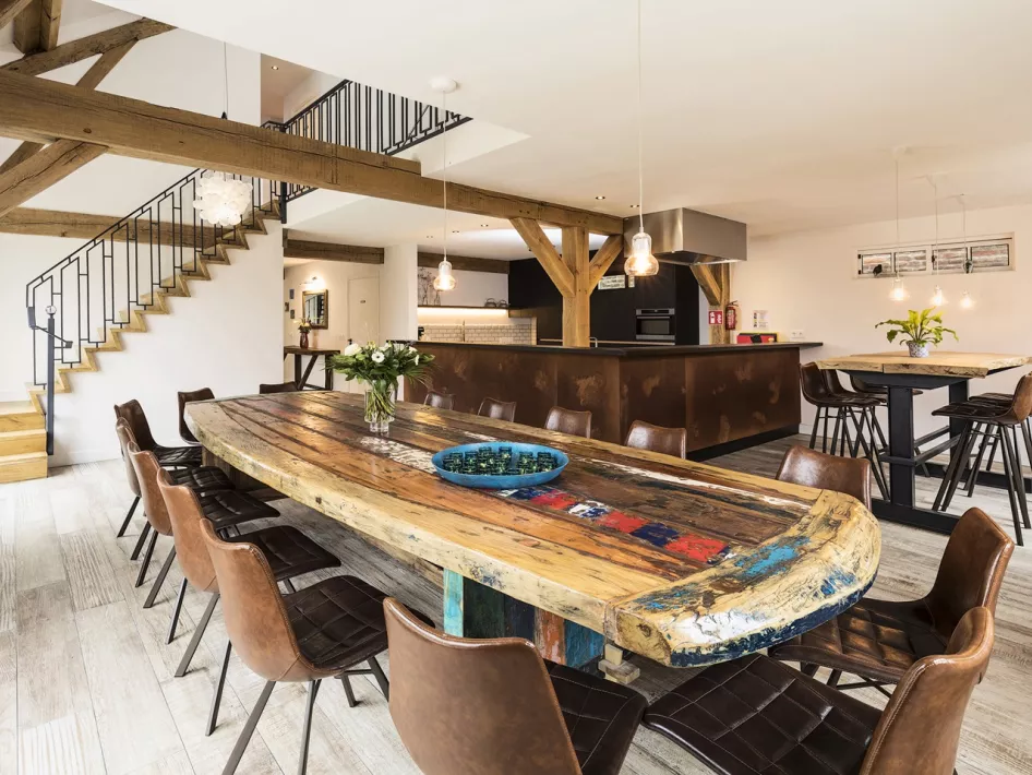 Ruime eetkamer in vakantieverblijf Eind 6 met een grote houten tafel, geschikt voor groepen tot 24 personen.