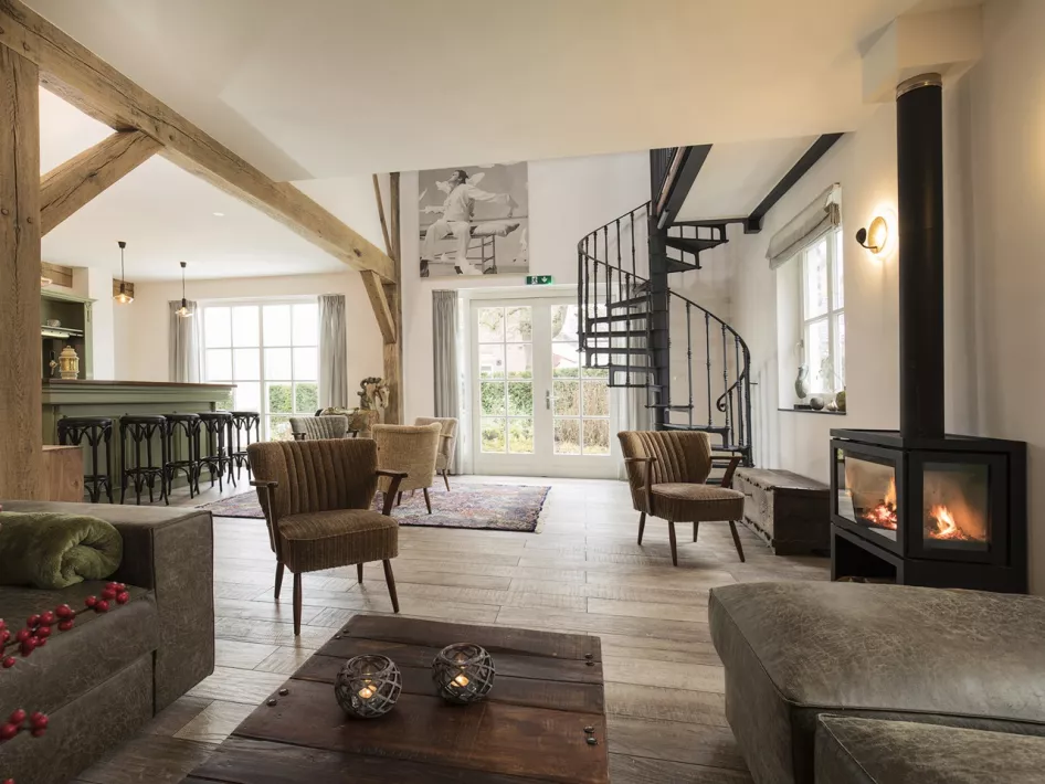 Moderne woonkamer in vakantieverblijf Eind 6, voorzien van een open haard, comfortabele zitplaatsen en een gezellige bar.