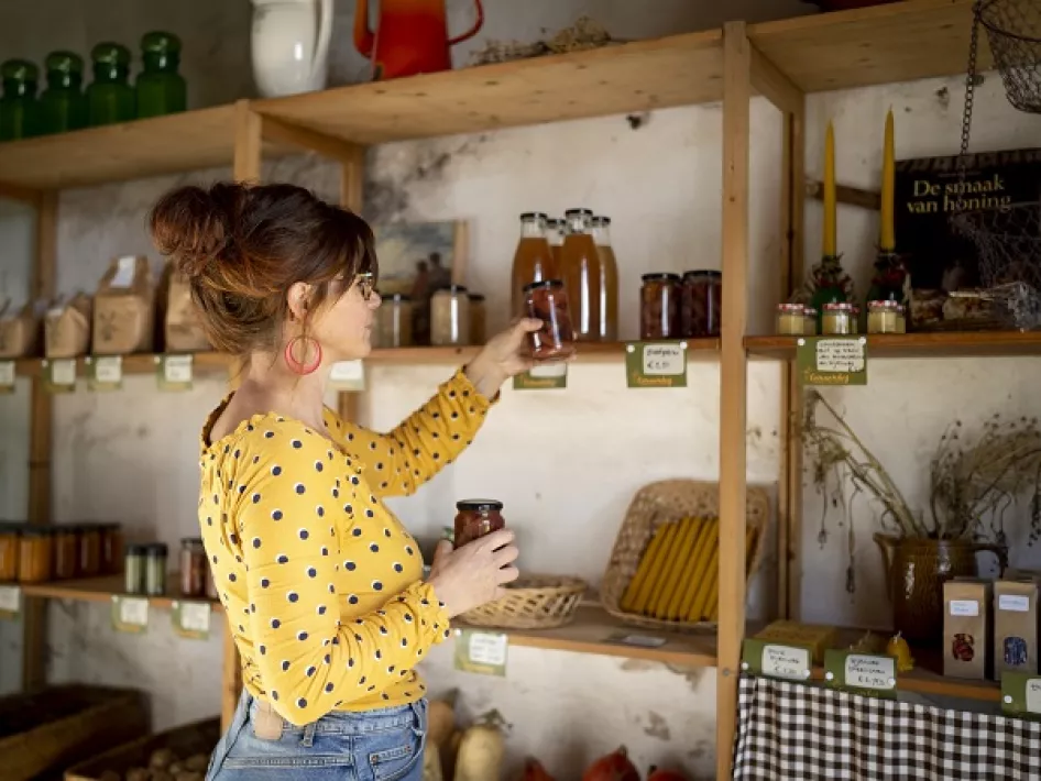 Frau füllt Regale im Hofladen des Genaenhofs auf
