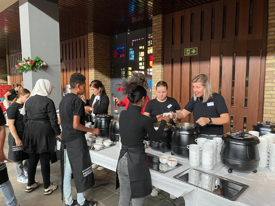 Leerlingen serveren soep aan deelnemers van Eten met Franciscus in Weert.