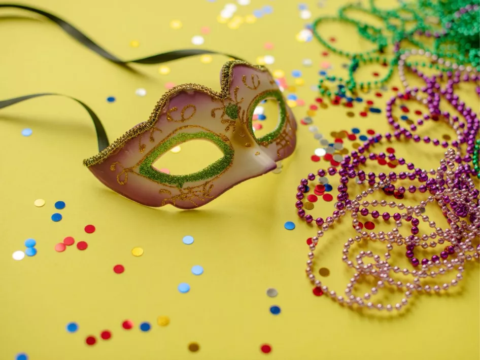 Carnavalsmasker met gekleurde kralen en confetti op een gele achtergrond tijdens Prinsentreffe Roermond 2026.