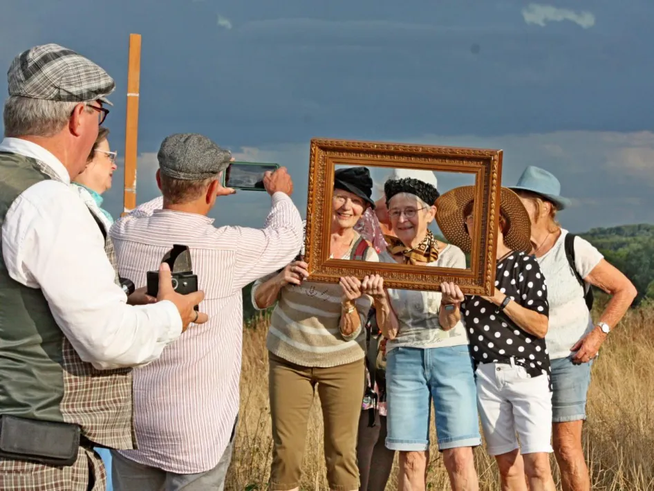 Deelnemers aan de Avond4Daagse Altweerterheide poseren met een schilderijlijst tijdens een act langs de route.