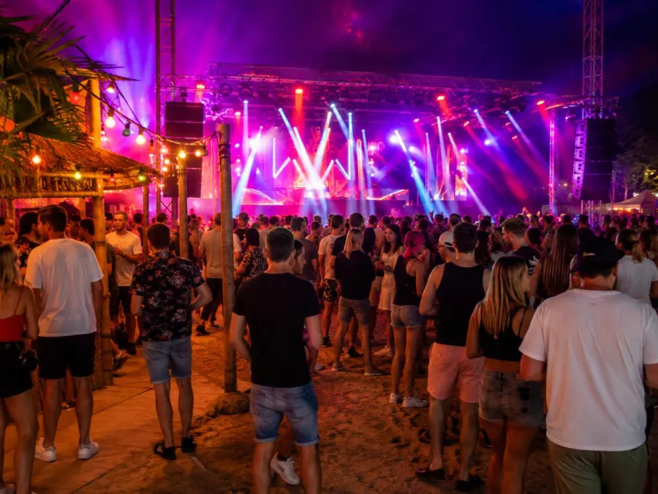 Besucher genießen die Bocholt Beach Party mit einer großen beleuchteten Bühne, farbenfrohen Lichteffekten und einem stimmungsvollen Festivalgelände, auf dem ausgelassen getanzt und gefeiert wird.