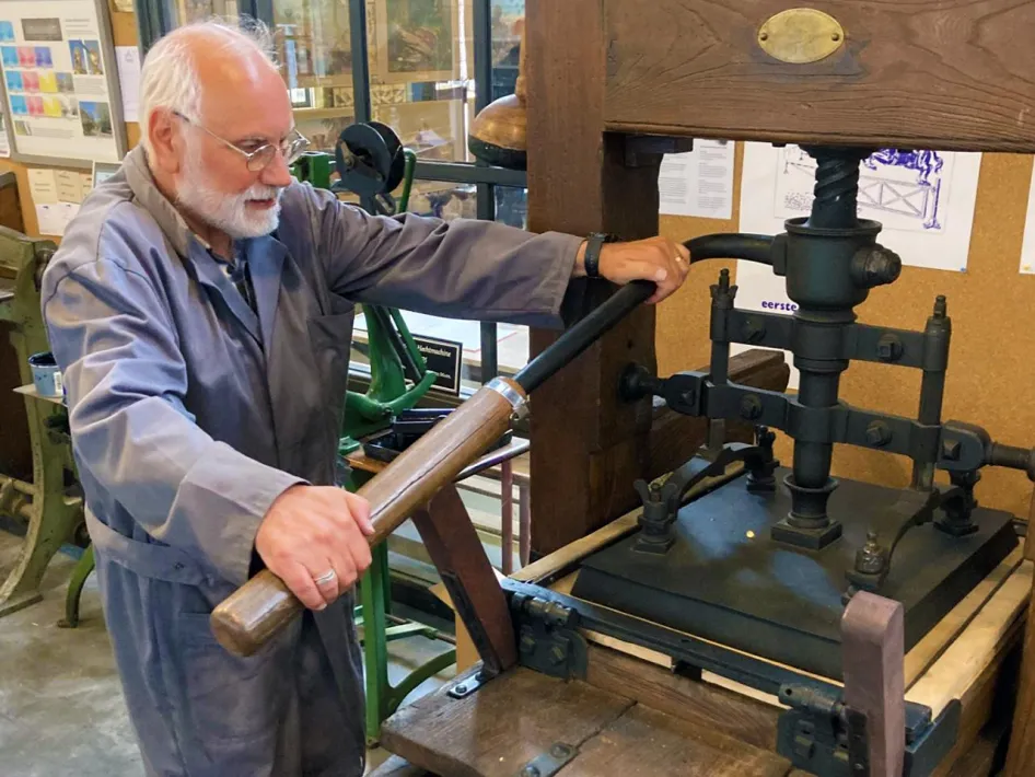 Vrijwilliger demonstreert een antieke drukpers tijdens Drukkersdag in Limburgs Openluchtmuseum Eynderhoof.