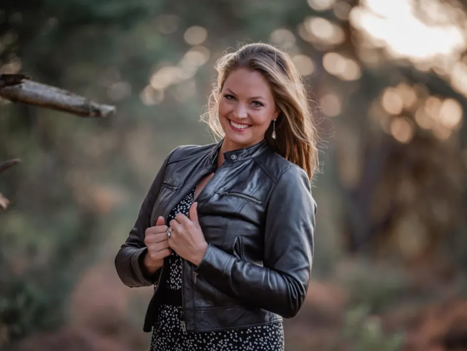 Sopraan Donij van Doorn poseert in een bosrijke omgeving, glimlachend in leren jasje.