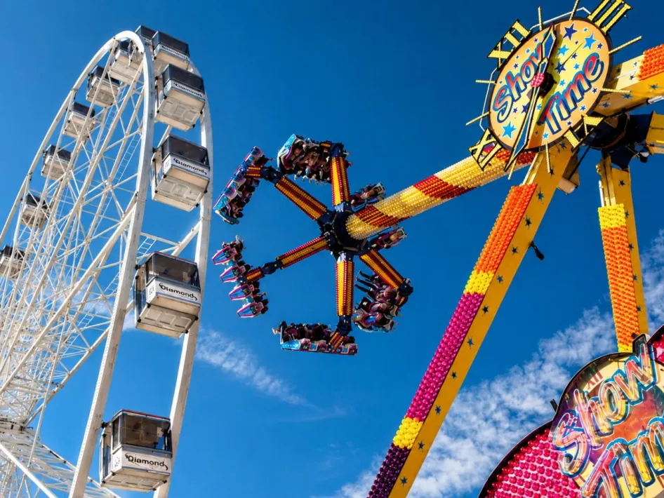 Reuzenrad en kleurrijke attractie tegen de blauwe lucht tijdens Kermis Weert.