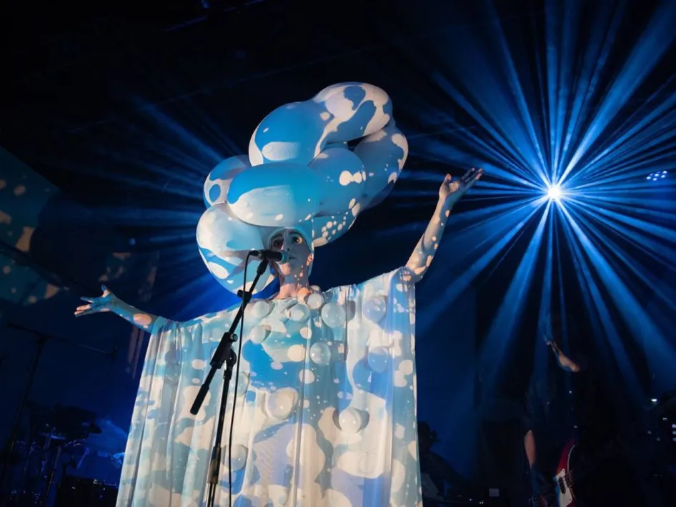 Zangeres in blauw-wit kostuum treedt op tijdens Limburg Festival, met fel blauw podiumlicht achter haar.