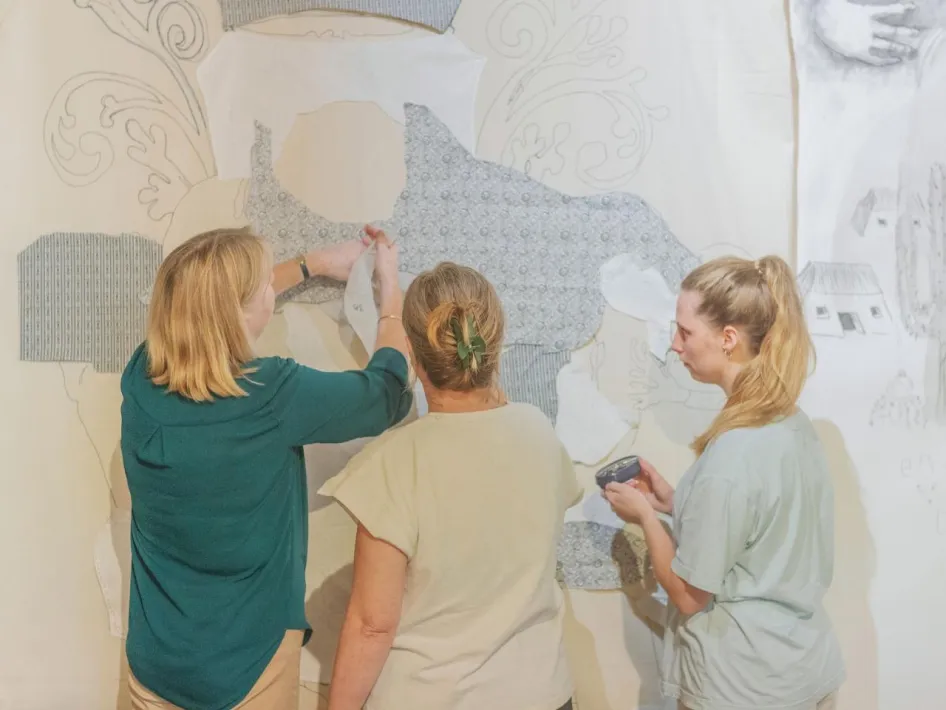 Groep vrouwen werkt samen aan ontwerp en opbouw van wandkleed