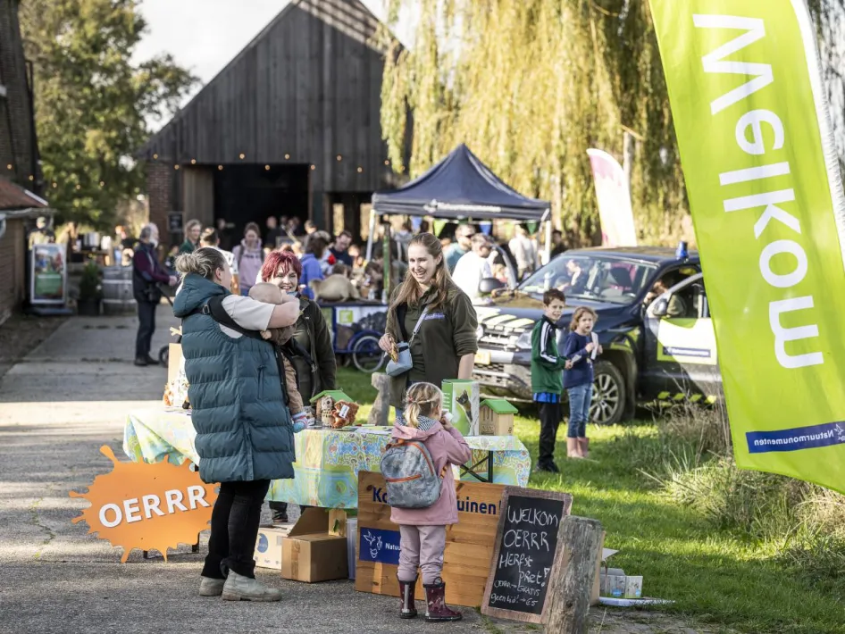 Kinderen ontdekken de natuur tijdens OERRR Herfstpret en voeren samen met begeleiders een opdracht uit bij een houten spelkast.