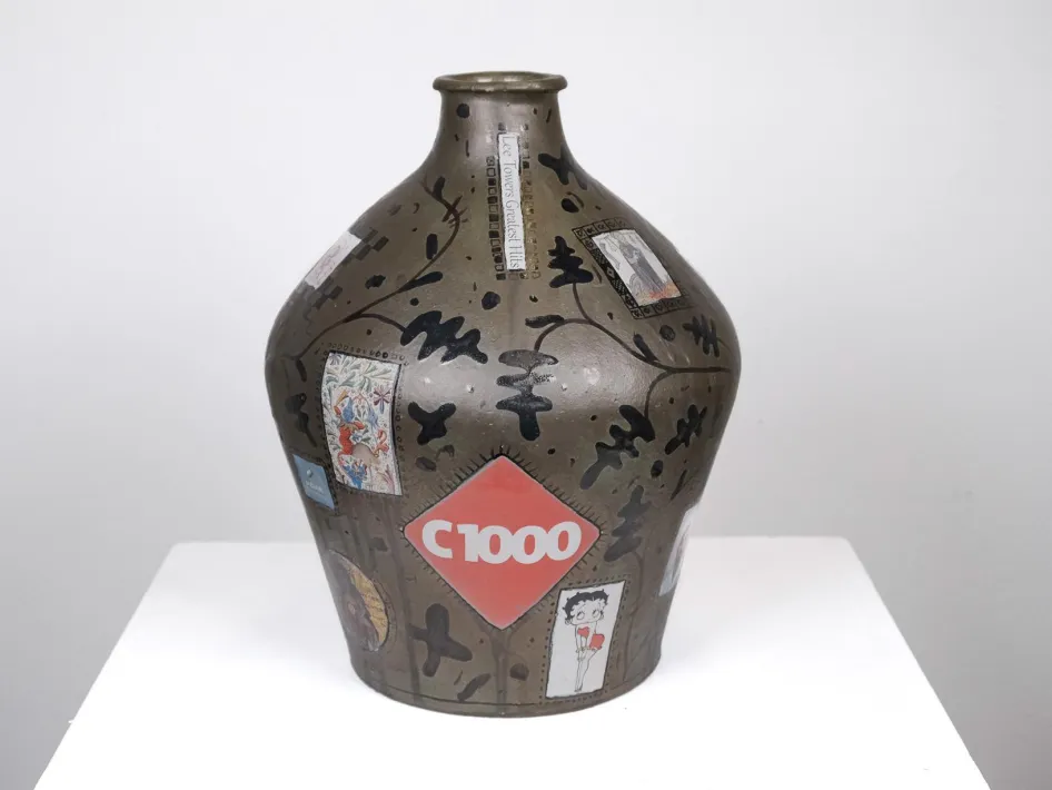 Dunkel glasiere Keramikvase mit collageartigen Abbildungen, Illustrationen und einer roten Fläche mit dem Schriftzug „C1000“.