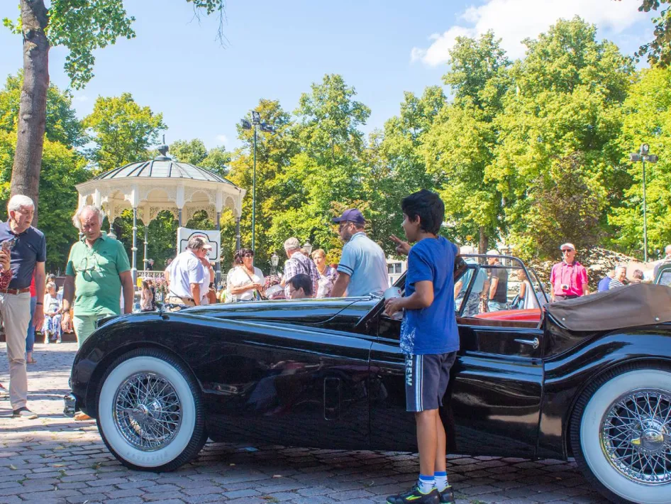 Bezoekers bekijken een klassieke cabriolet tijdens Roermondvol Oldtimers in het stadspark van Roermond.