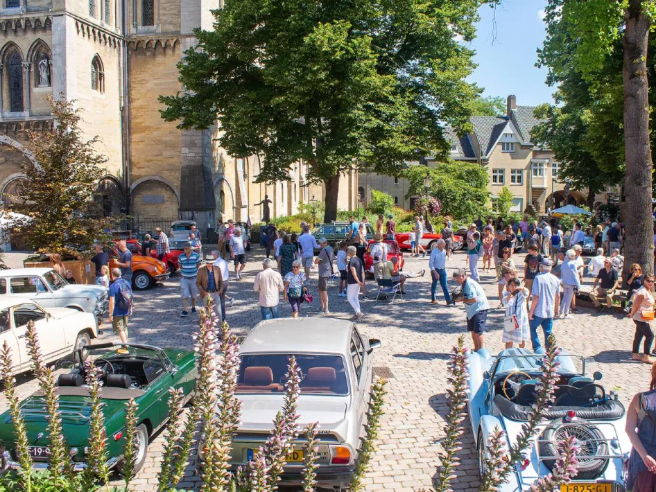 Sfeervol overzicht van klassieke auto's en bezoekers tijdens Roermondvol Oldtimers op het Munsterplein in Roermond.