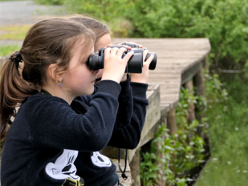 Kinderen kijken met verrekijkers naar de natuur tijdens de sPeelse Beleeftocht op de Dag van het Nationaal Park in De Groote Peel.