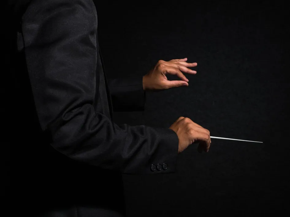 Een dirigent houdt een baton vast tijdens Twee orkesten, één baton