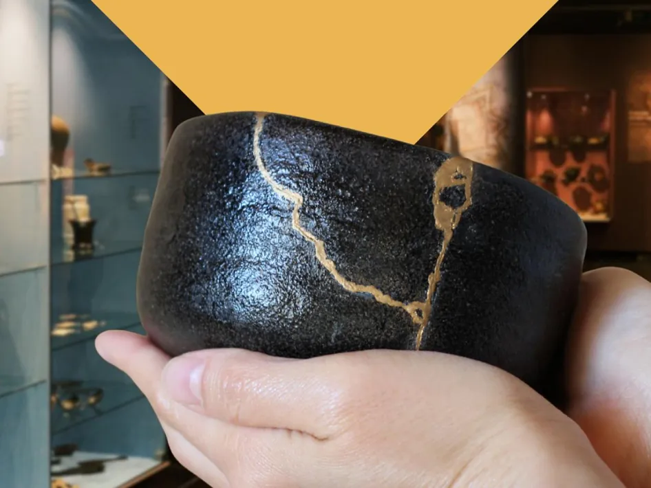 Workshop Kintsugi: een zwarte keramieken kom met goudkleurig herstelde barsten wordt vastgehouden in een archeologisch museum in Musea Maaseik.