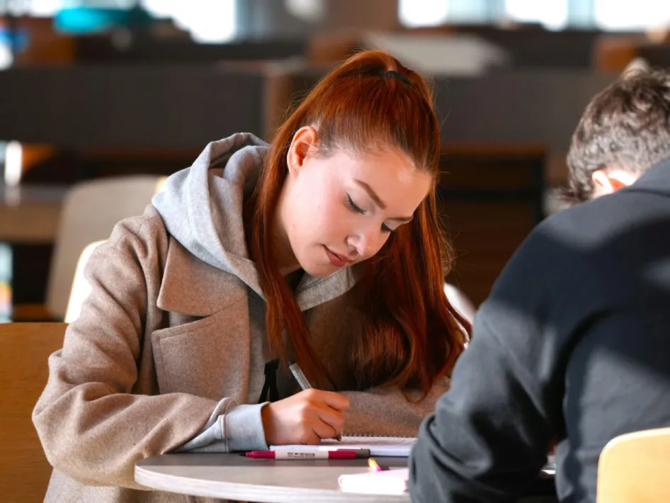 Leerling schrijft geconcentreerd aan tafel tijdens het studeren voor examens