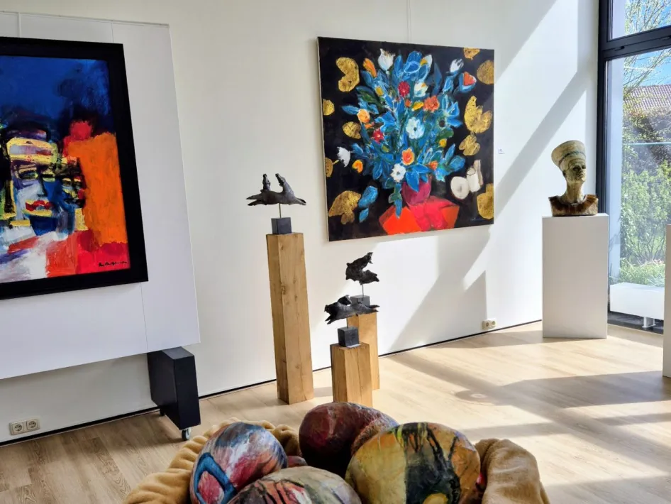 Expositie in Heythuysen bij galerie Bont & Blauw met kleurrijke schilderijen, sculpturen en beschilderde eieren in een lichte ruimte