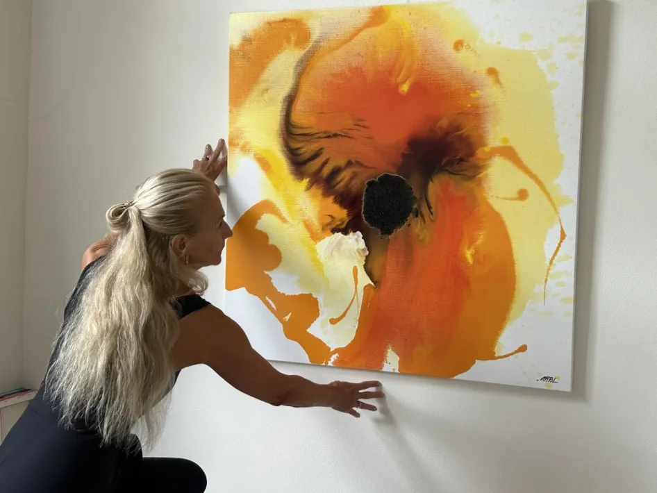 Mathilde Pil hangt een van haar schilderijen op tijdens de tentoonstelling Hoop
