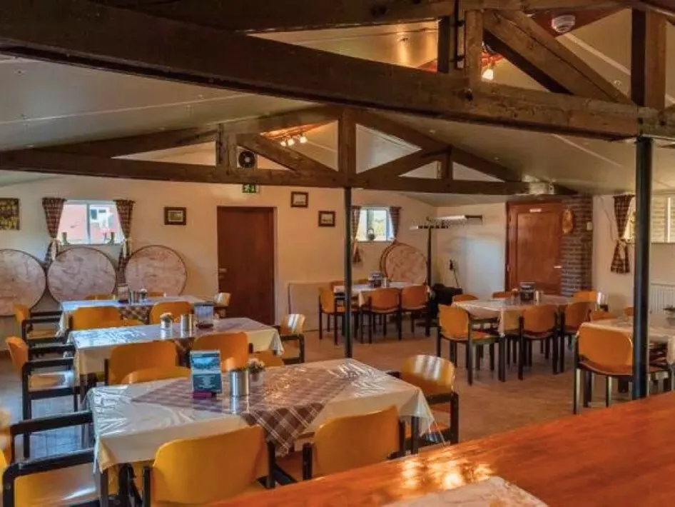 Atmospheric room at Vurenhof in Posterholt, with wooden beamed ceiling, covered tables and yellow chairs, suitable for parties, meetings and group activities.
