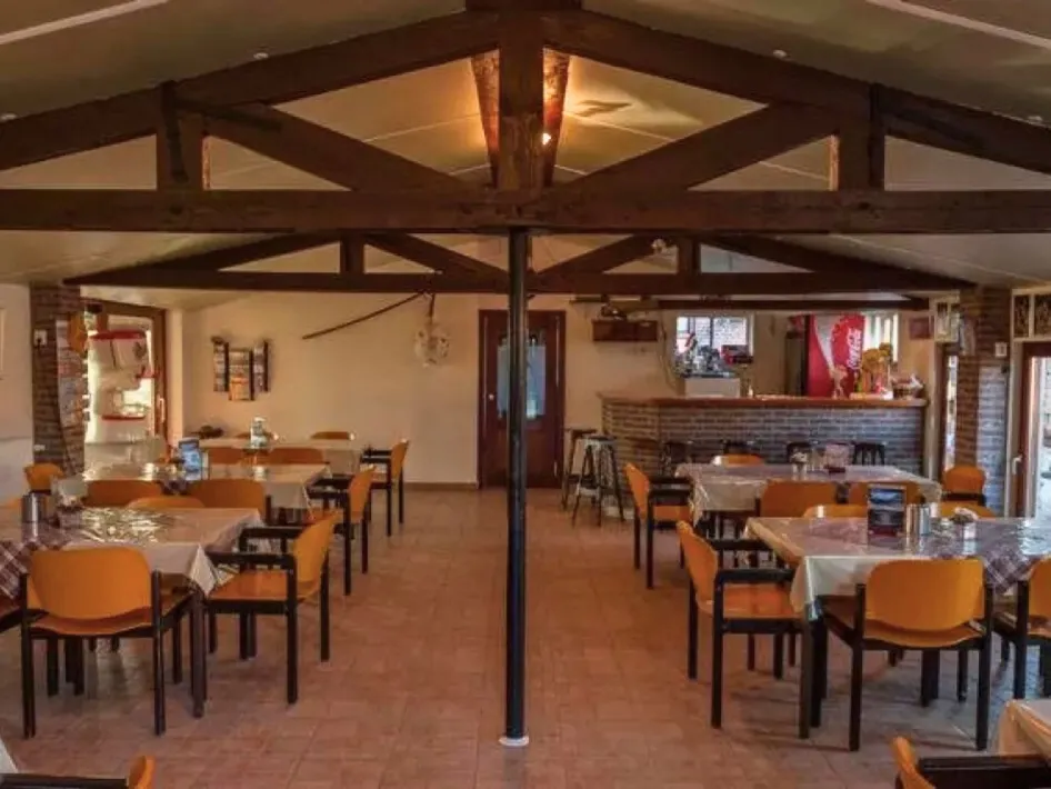 Gezellige landelijke zaal met houten balkenplafond, gedekte tafels en een bar, geschikt voor groepsbijeenkomsten en feesten bij Vurenhof in Posterholt.