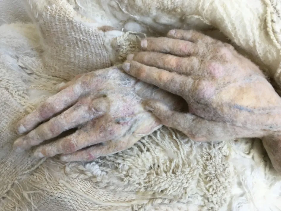 Gevilte handen van wol, rustend op een zachte wollen deken.