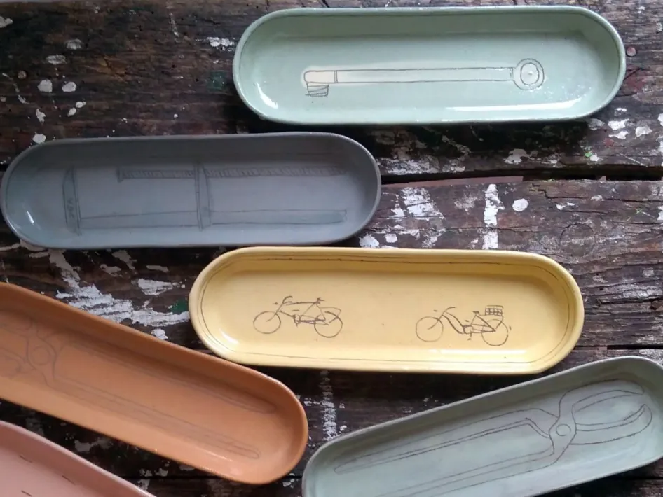 Drie robuuste, handgemaakte keramische borden met verschillende texturen en patronen op een houten ondergrond, omringd door natuurvondsten zoals stenen en stukjes hout.