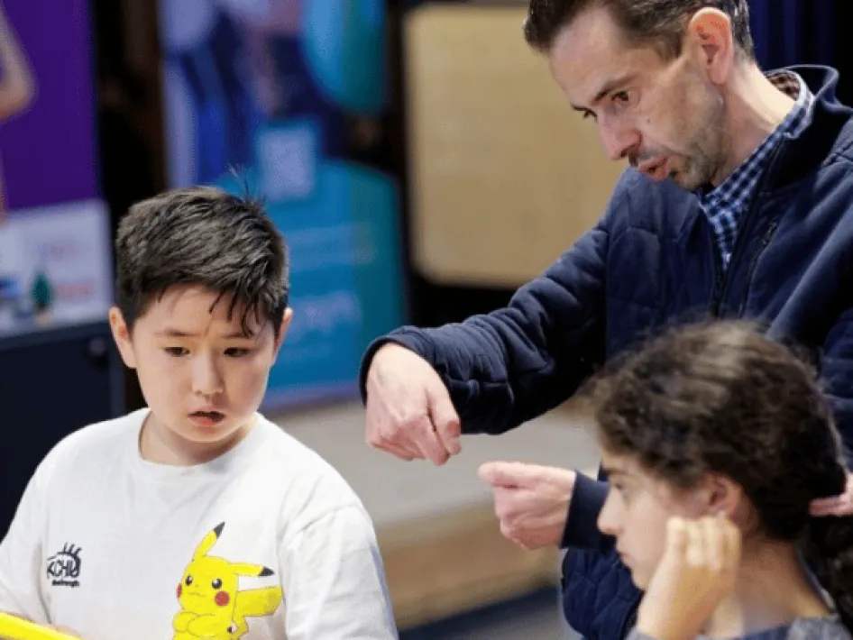 A man is explaining something to two children.