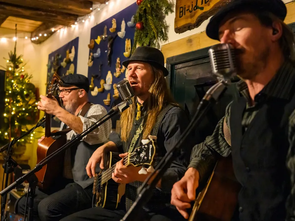 Muzikanten verzorgen een liveoptreden tijdens het Eynder Pieck Festeyn in Openluchtmuseum Eynderhoof, omringd door sfeervolle kerstversiering.