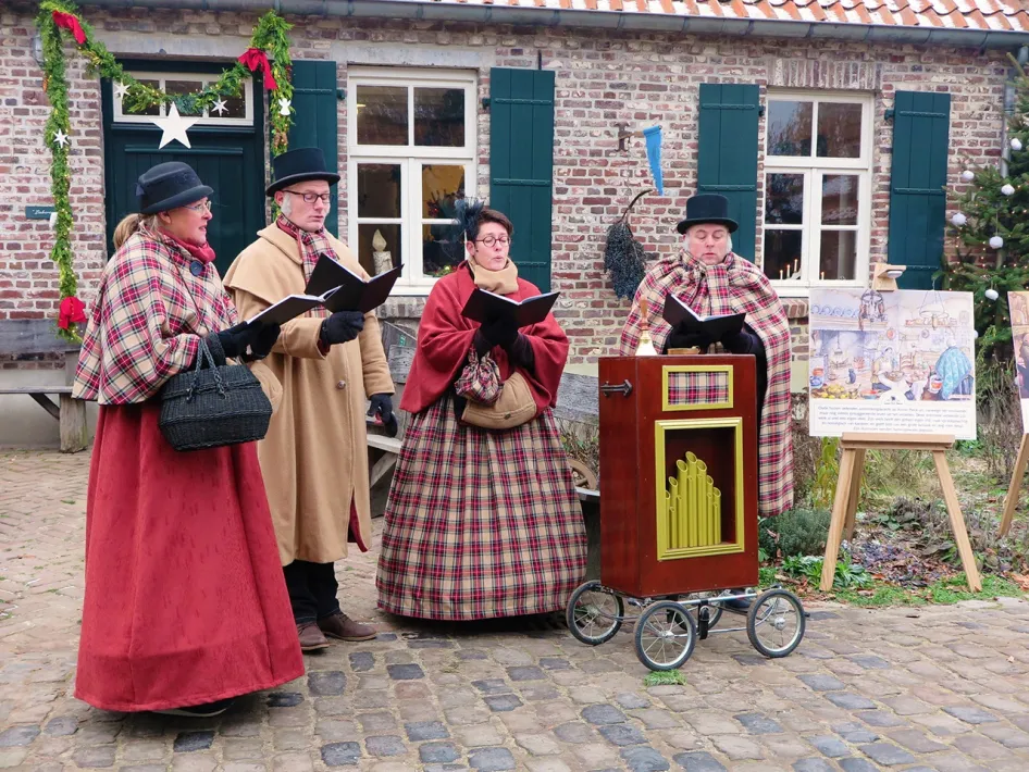 Zanggroep in Victoriaanse kledij zingt kerstliederen voor het museumgebouw tijdens Eynder Pieck Festeyn.