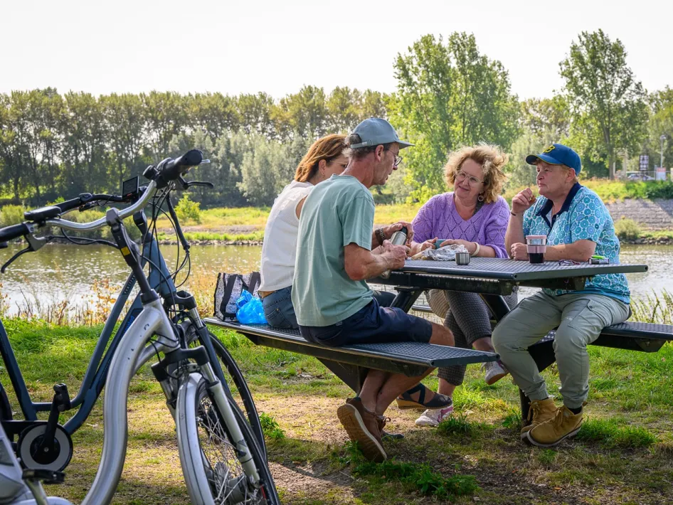 Cyclists enjoy a picnic by the water of the Maasplassen during the Meuse Towns Cycle Route.