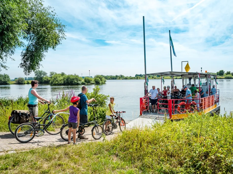 Fietsers steken de Maas over met het veerpont tussen Neer en Rijkel tijdens de fietsroute Moeder Maas.