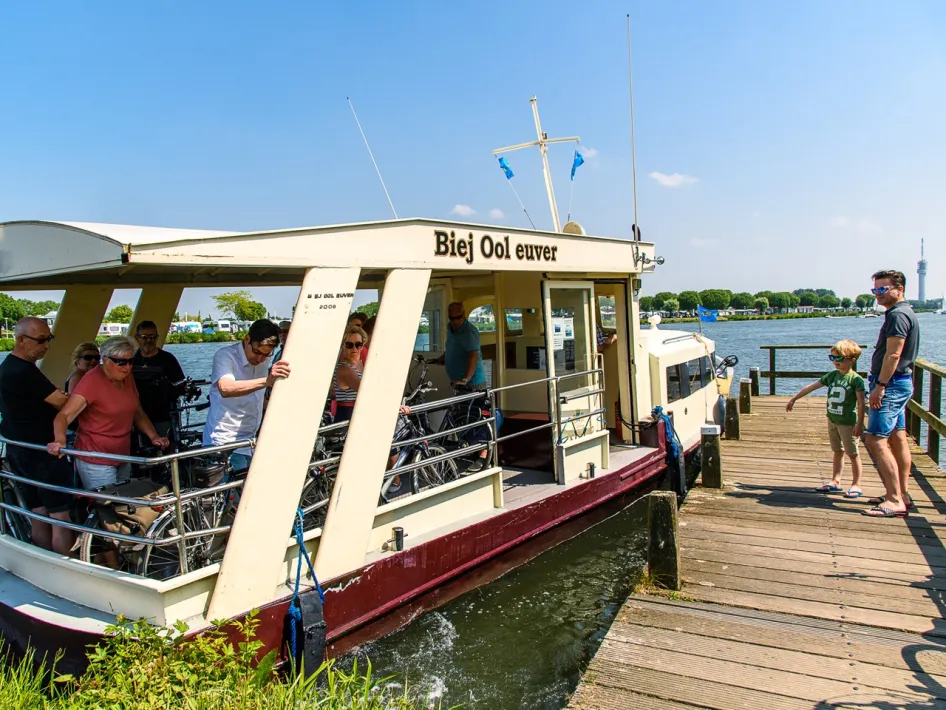 Fietsers en wandelaars stappen op veerpont Biej Ool Euver, die de oversteek maakt tussen Ool en Roermond over de Maas.