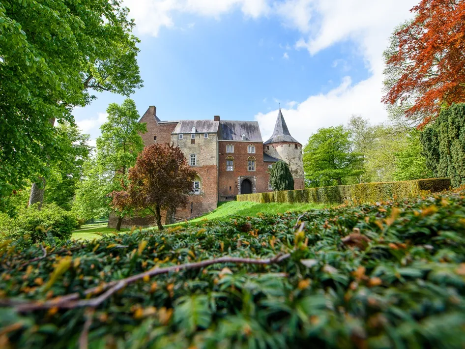 Kasteel Horn, een prachtig middeleeuws kasteel omringd door groen, met zijn karakteristieke toren en rode bakstenen muren.