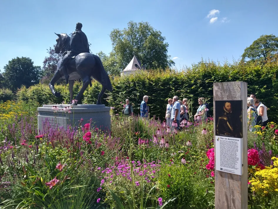 Beeld van Filips van Montmorency in het kasteelpark Nijenborgh in Weert, met bezoekers en bloeiende bloemen