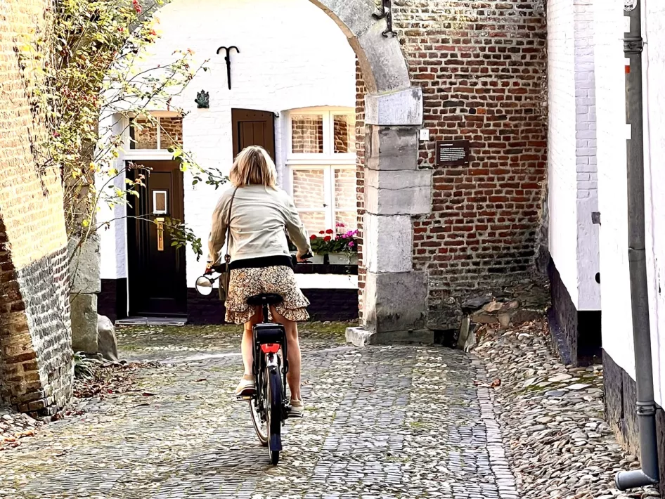 Vrouw fietst door de smalle, witte straatjes van Thorn tijdens de fietsroute langs Prinsessen, Heksen en Maria
