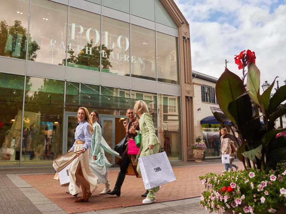 Vrolijke groep vrouwen met shoppingtassen loopt langs de Polo Ralph Lauren winkel bij Designer Outlet Roermond tijdens het Friends & Family Event.