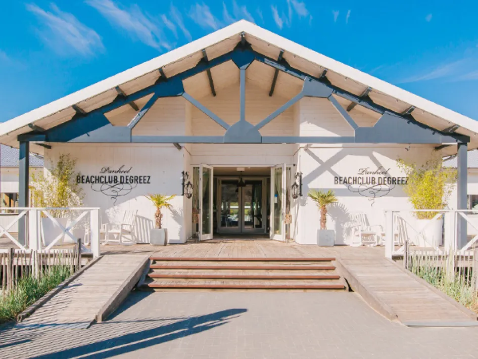 Entrance of Beachclub Degreez with wide wooden stairs and inviting doorway.